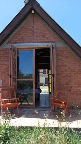 a red brick building with two benches in the doorway at Cabaña AAA in Chuí