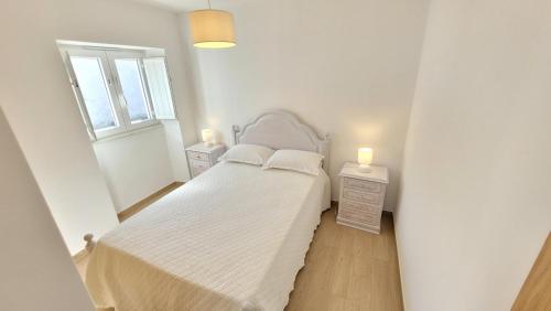 a white bedroom with a bed and two night stands at Casa da Costureira in Brejao