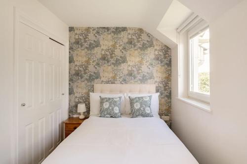 a bedroom with a large white bed with a window at Ty Venda in Pembrokeshire