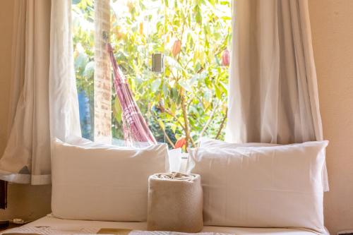 a bed with two pillows in front of a window at Villa Residencial Encantos Da Mata in Itacaré