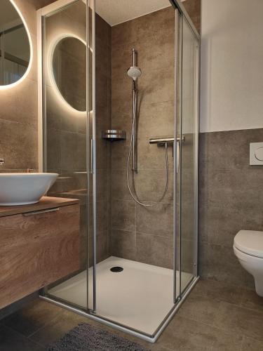 une salle de bain avec une douche avec un lavabo et des toilettes dans l'établissement Sunnustrahl, à Grächen