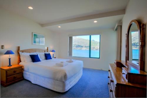 a bedroom with a large white bed and a window at Frankton House - Queenstown Holiday Home in Queenstown