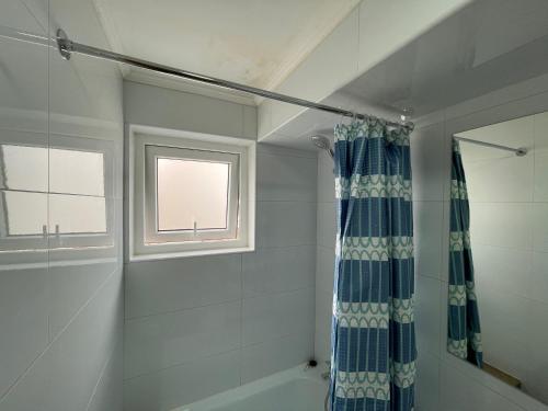 a bathroom with a blue shower curtain and a window at TinyApartments - estudio pleno centro Concepción in Concepción