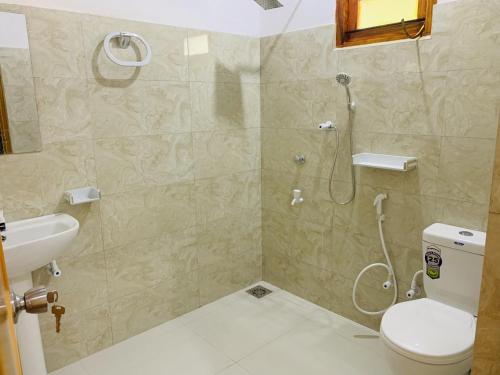 a bathroom with a shower and a toilet and a sink at Coco Garden Holiday Homes in Anuradhapura