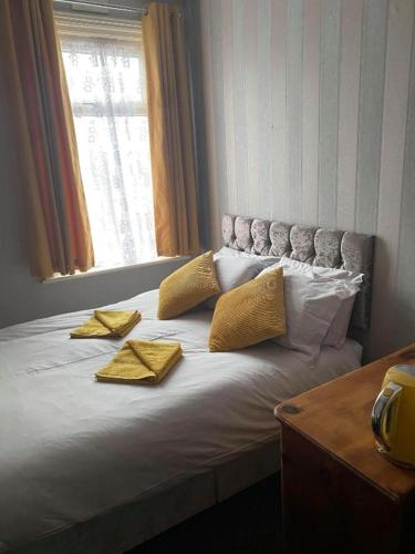 a bed with two yellow pillows and a window at JEANNE in Blackpool