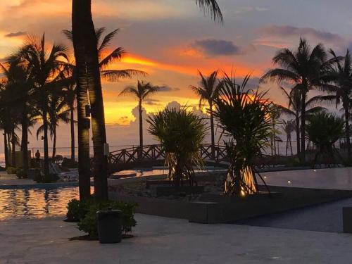 a sunset at a resort with palm trees and water at Casa Ohana Acapulco Diamante in Acapulco