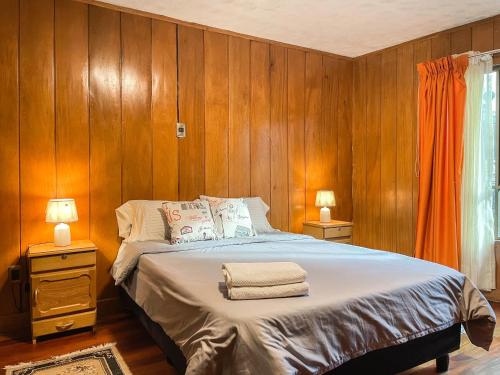 a bedroom with a bed with wooden walls and two lamps at Casa Abaroa in La Paz