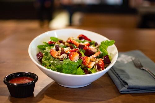 a salad in a white bowl on a wooden table at Hotel San Angel in Hermosillo