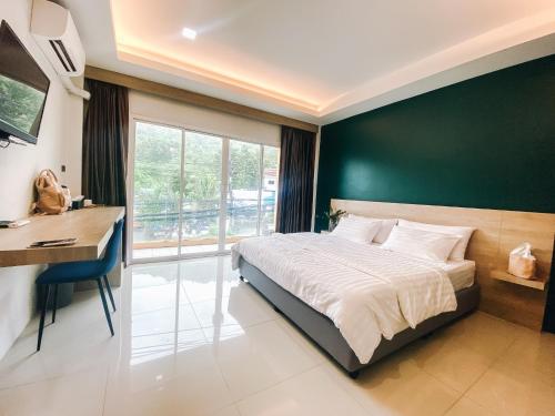 卡塔海灘的住宿－Tall Tree Kata Phuket，一间卧室设有绿色的墙壁、一张床和一张书桌