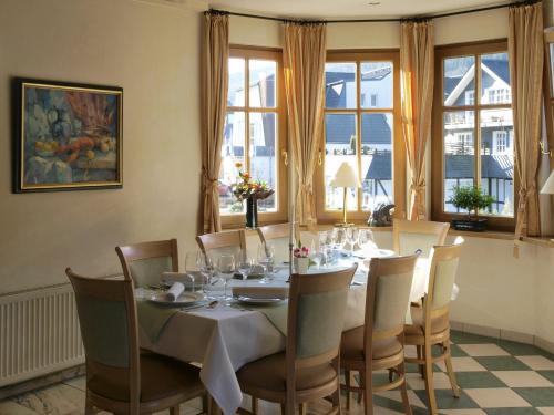 a dining room with a table and chairs and windows at Landhaus Silberberg in Winterberg