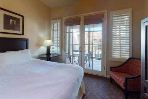 een slaapkamer met een bed en een stoel en een balkon bij LV102 Upstairs 1 Bedroom Legacy Villas Delight in La Quinta