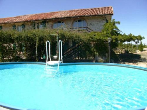 a large blue swimming pool in front of a house at Agriturismo Cascina Serra in Cossano Belbo