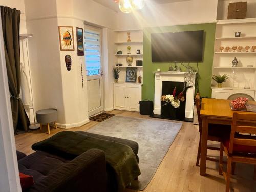 a living room with a couch and a tv and a table at Lovely 2 bed Hampstead Apartment in London
