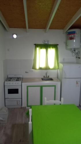 uma cozinha com uma mesa verde e um lavatório em Departamento para 4 primer piso em Valeria del Mar