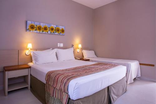 a hotel room with two beds and two lamps at Ciribaí Praia Hotel in Pauba
