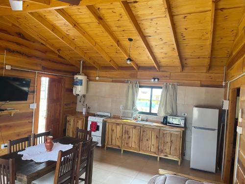 cocina con techo de madera, mesa y nevera en Complejo Anthea en Villa Yacanto