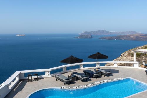 a pool with chairs and umbrellas next to the water at Athermi Suites - Adults Only in Megalokhori