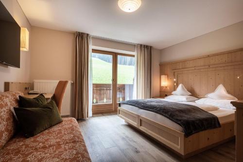 sypialnia z dużym łóżkiem i oknem w obiekcie Hotel Baumwirt w mieście Castelrotto