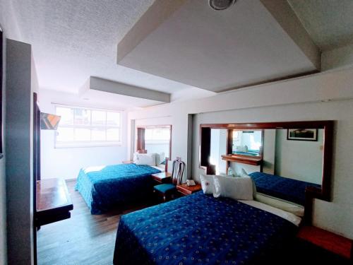 een hotelkamer met 2 bedden en een spiegel bij Hotel Mina in Mexico-Stad
