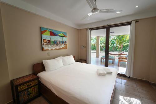 a bedroom with a large white bed and a sliding glass door at Sol y Sombra in Bocas Town