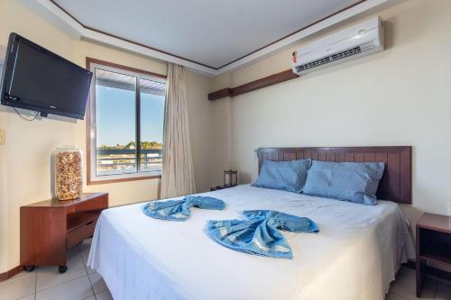 a bedroom with a bed with a tv and a window at Condomínio Blue Marlim por Carpediem in Parnamirim