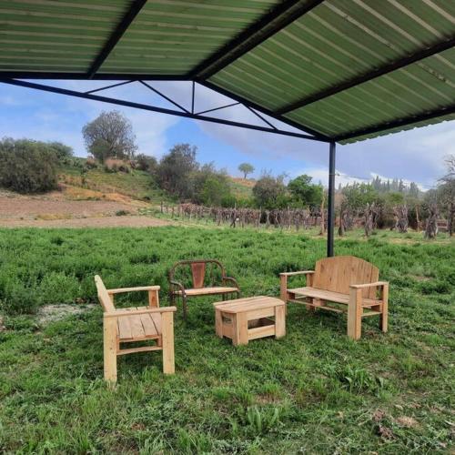 a group of benches sitting under a canopy in a field at Cabaña Girasoles Mi Campito Cachi Salta in Cachí
