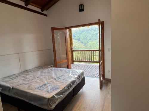 卡曼杜卡亞的住宿－Casa de luxo em Monte Verde，一间卧室设有一张床,并有通往阳台的门