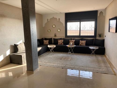 a living room with a black couch and two tables at Agadir well in Mirleft