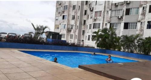 two people in a swimming pool in front of a building at APARTAMENTO 3 habitaciones y piscina a solo 15 minutos del aeropuerto in Panama City