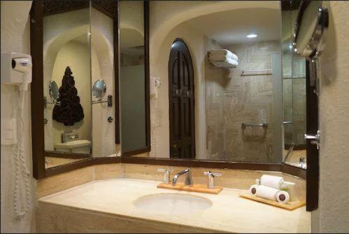 a bathroom with a sink and a large mirror at GR Caribe Deluxe All Inclusive in Cancún