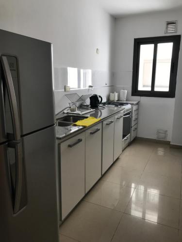 una cocina con nevera de acero inoxidable y armarios blancos en Departamento de categoría en macrocentro Echeverria en Río Cuarto