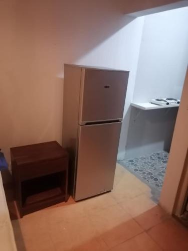 a stainless steel refrigerator in a kitchen with a table at SUITE HUTAMI in Vila Praia Do Bilene