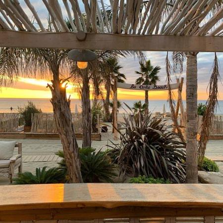 a wooden bench in front of a beach with a sunset at Coco in Canet-en-Roussillon
