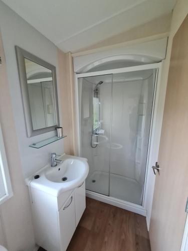 a white bathroom with a shower and a sink at 89 Main Park , Lilliardsedge in Harrietsfield