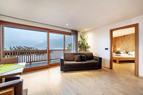 a living room with a couch and a balcony at Residence Kalchgruberhof Zirbe in Santa Valpurga