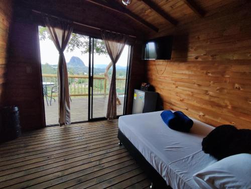 Schlafzimmer mit einem Bett und Blick auf eine Terrasse in der Unterkunft Breeze Glamping -Guatape in El Peñol