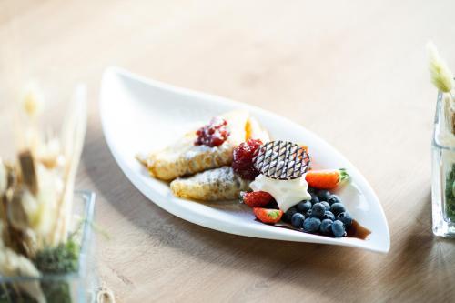 a plate of food with fruit on a table at Hotel Tisa Pohorje in Pohorje