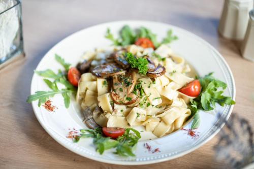 a plate of pasta and vegetables on a table at Hotel Tisa Pohorje in Pohorje