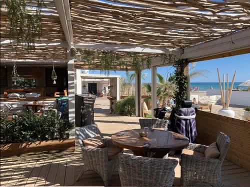 patio z drewnianym stołem i krzesłami oraz plażą w obiekcie KiWi w mieście Canet-en-Roussillon
