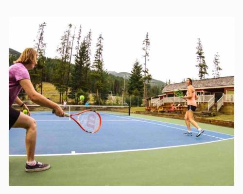 two women playing tennis on a tennis court at Aurora Townhomes by StayIn in Panorama