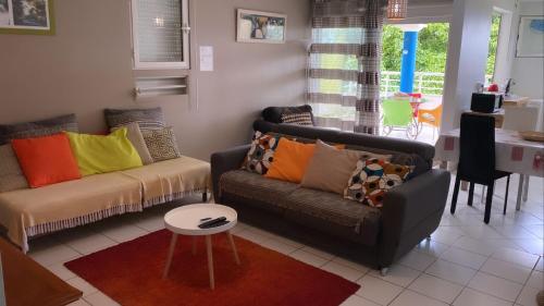 a living room with two couches and a table at f3 location saisonnière détente tranquillité et belle vue in Les Trois-Îlets