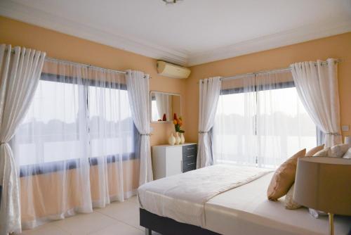 a bedroom with two large windows with white curtains at Atlantic Luxury Apartments in Bakau