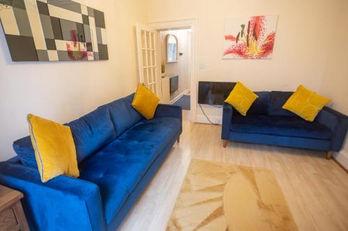 a living room with a blue couch and yellow pillows at Sandgate 2-Bed Apartment in Ayr central location in Ayr