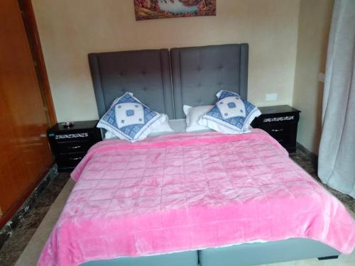 1 dormitorio con 1 cama rosa y 2 mesitas de noche en Luxurious Moroccan Villa Discover the Magic of Moorish Design, en Marrakech