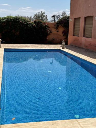 a large blue swimming pool next to a building at Luxurious Moroccan Villa Discover the Magic of Moorish Design in Marrakesh
