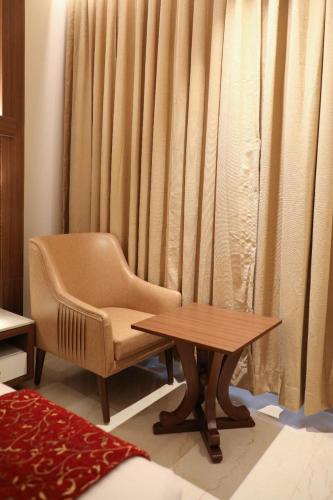 a chair and a table in front of a curtain at Hotel Gurudev Grand in Kalyan
