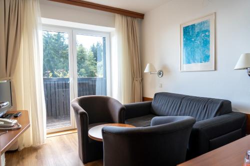 a living room with a couch and chairs and a window at Hotel Tisa Pohorje in Pohorje