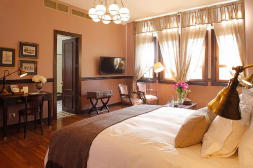 a bedroom with a large white bed and a desk and a table at Hotel Boutique Castillo Rojo in Santiago