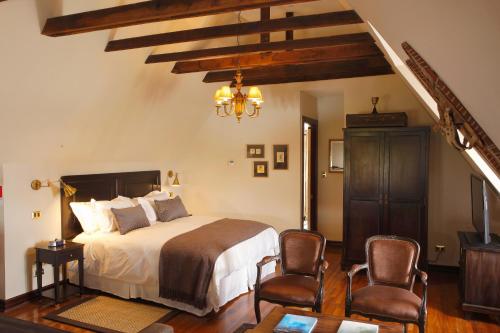 a bedroom with a large bed and two chairs at Hotel Boutique Castillo Rojo in Santiago