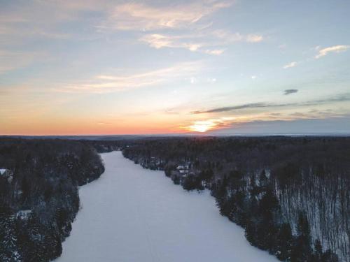 een luchtzicht op een rivier bij zonsondergang met bomen bij Chalet Silver Fox SPA at Fiddler's Lake in Mille-Isles